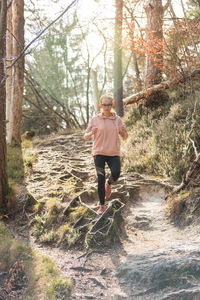 Woman running on street amidst trees in forest