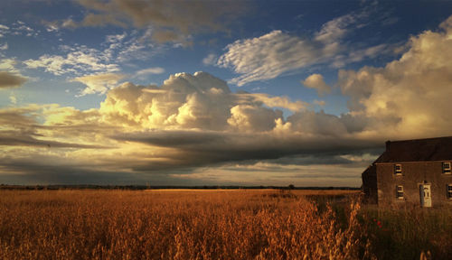 View of field against cloudy sky