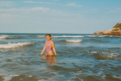 Rear view of woman standing at beach against sky