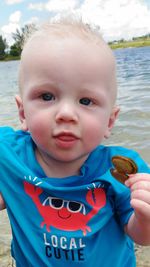 Portrait of toddler holding clam shell standing at lakeshore