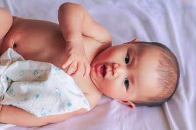 Portrait of cute baby lying on bed