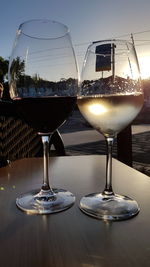 Wine glasses on table at restaurant against sky during sunset