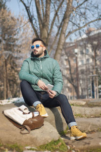 Portrait of young man sitting against trees