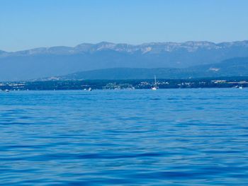 Scenic view of calm sea against mountain range