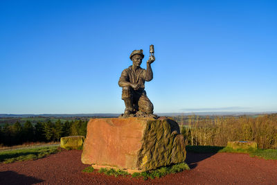 Low angle view of statue against clear blue sky