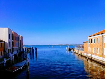 Scenic view of sea and buildings against clear blue sky