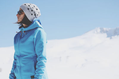 Woman wearing sunglasses standing on snow covered mountain