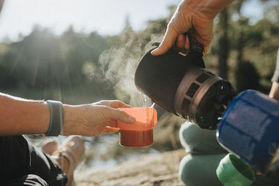 Two women preparing hot drink at campsite at lakeshore