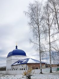 Church by building against sky during winter