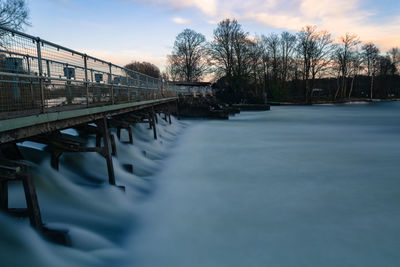 Bridge over canal against sky during winter
