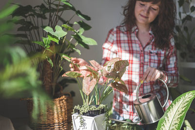 Portrait of young woman holding potted plant