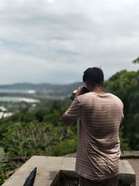 Rear view of young man looking through binoculars at observation point