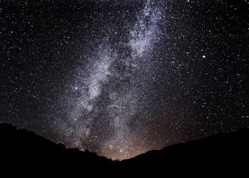 Silhouette landscape against star field at night