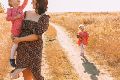 Mom with twins, holding a baby in her arms. the girl smiles and walks along the road
