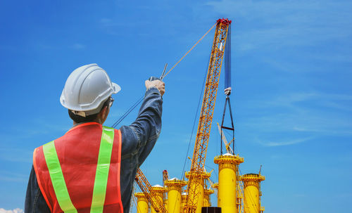 Low angle view of crane at construction site against sky