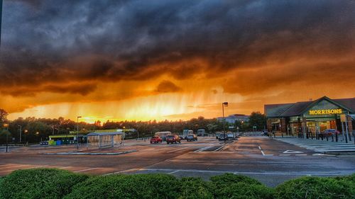 Cars parked on road against cloudy sky