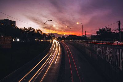 Light trails on road against sky at night