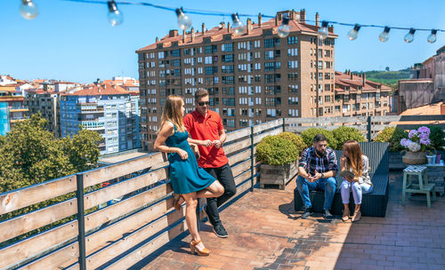 Couple talking next to friends in rooftop on a summer day