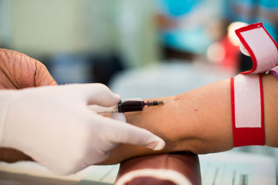 Cropped hands of nurse taking blood sample of patient at hospital