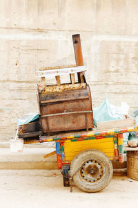 Multi colored push cart on sidewalk against wall