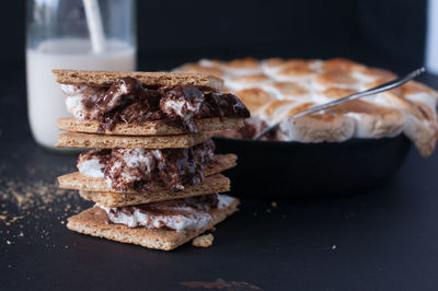 Stack three s' mores melted in a skillet and a bottle of milk