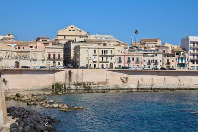 Buildings in city against clear blue sky