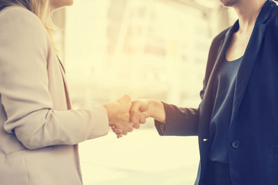 Midsection of businesswoman shaking hand with colleague