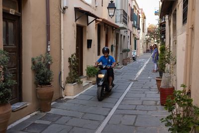 Rear view of man riding bicycle on street amidst buildings in city