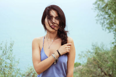 Portrait of young woman standing against clear sky