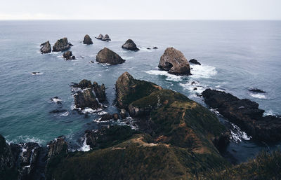 Headlands in calm sea against the sky