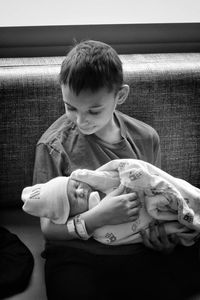 Boy with baby girl sitting on sofa at home