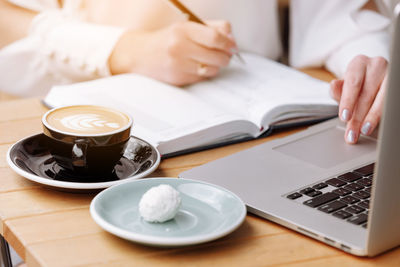 Midsection of woman using laptop at table