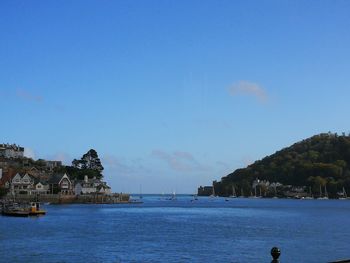 Scenic view of sea by town against clear blue sky