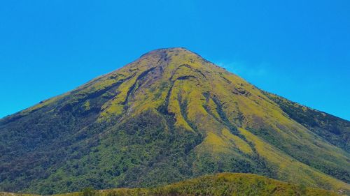 Low angle view of volcanic mountain against clear blue sky