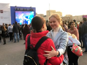 Happy friends talking while standing in city