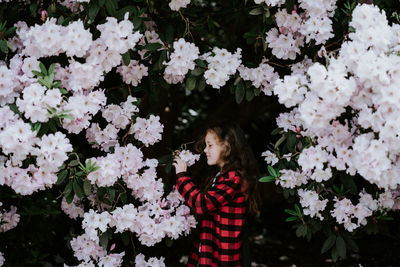 Side view of girl standing amidst flowering plants at park
