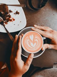 High angle view of hand holding coffee cup on table