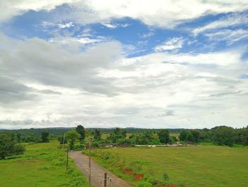 Scenic view of grassy field against cloudy sky