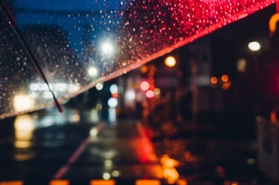 Close-up of wet illuminated road in city at night