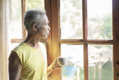 Side view of man drinking coffee cup at home