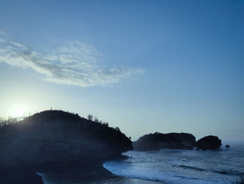 Scenic view of rocks on beach against blue sky