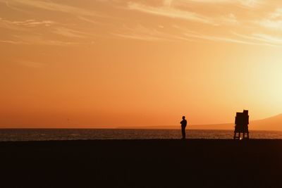 Silhouette of people on beach at sunset