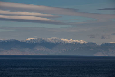 Scenic view of sea and snowcapped mountains against sky