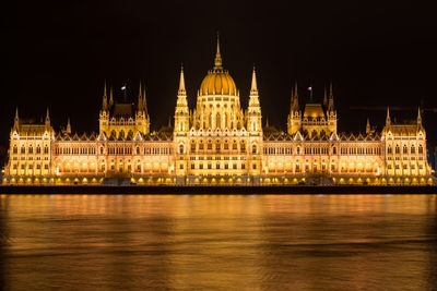 Illuminated hungarian parliament building by danube river at night