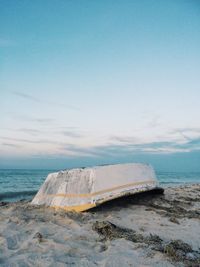 Boat moored at beach against sky during sunset