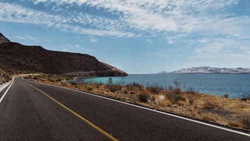 Road by mountains against sky