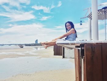 Woman sitting on beach against sky