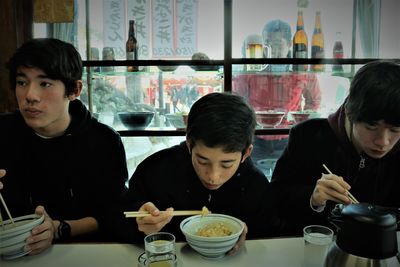 Boys looking away while sitting on table