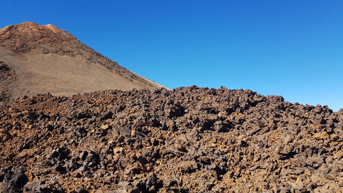 Scenic view of rocky mountains against clear blue sky, walking on a volcano