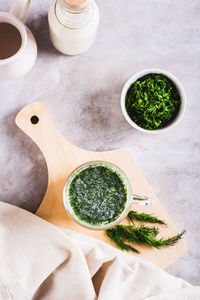 Glass with fresh turkish ayran with dill and greens on the table top and vertical view